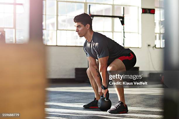 gym instructor lifting kettlebell at urban gy - hurken stockfoto's en -beelden