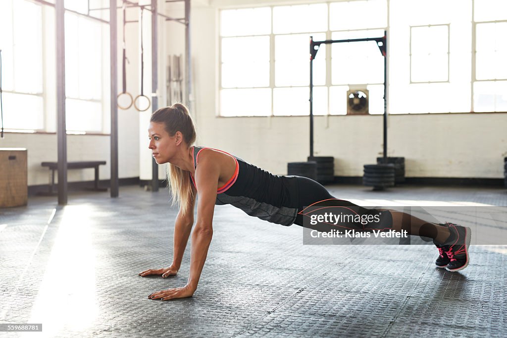 Woman making pushup's in gym at sunrise