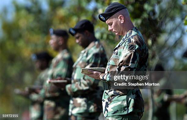 Staff Sgt. Randy Olinger bows his head in prayer during a memorial tree dedication ceremony to honor soldiers who have died in Iraq October 20, 2005...