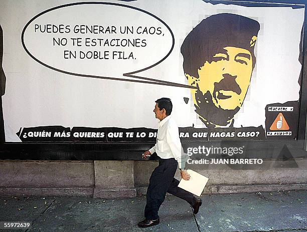 Man walks by a poster with an image of ousted Iraqi President Saddam Hussein and a speech ballon reading: "You may generate chaos, don't double-park"...