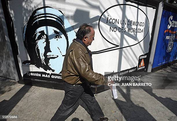 Man walks by a poster with an image of Mother Teresa of Calcutta and a speech ballon with a typical Mexican untranslatable expression which...