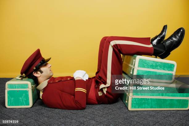 bellboy reclining on suitcases - bell boy stock pictures, royalty-free photos & images