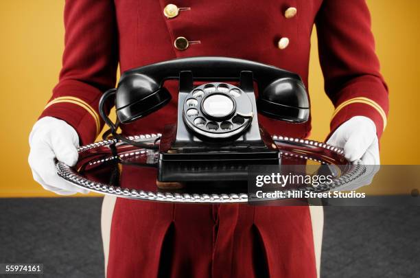 bellboy delivering telephone on silver platter - silbertablett stock-fotos und bilder