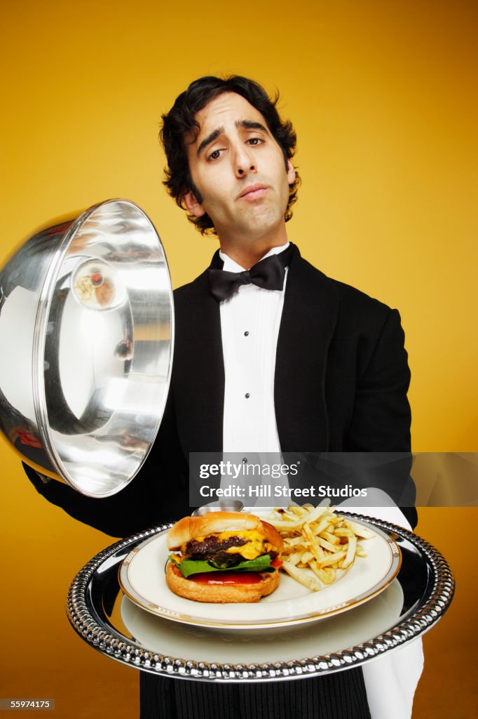 Waiter delivering hamburger on silver platter