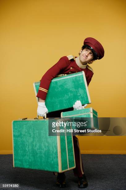 bellboy carrying heavy luggage - bellhop stockfoto's en -beelden