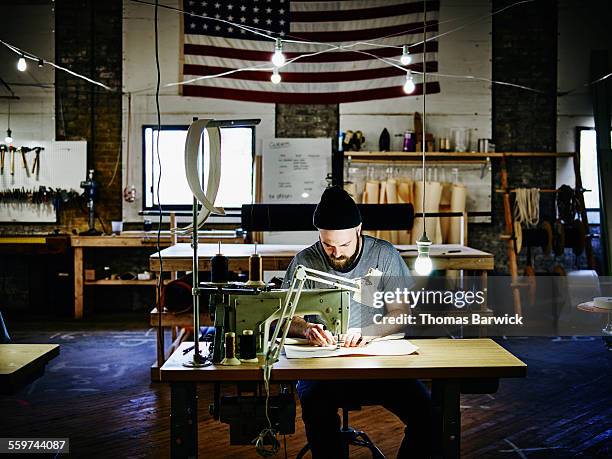 man sewing canvas bag at industrial sewing machine - stitching imagens e fotografias de stock
