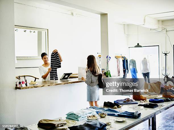 smiling shop owner helping customer with purchase - clothes shop counter stock pictures, royalty-free photos & images