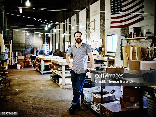smiling leatherworker standing in studio - tシャツ　キャップ ストックフォトと画像
