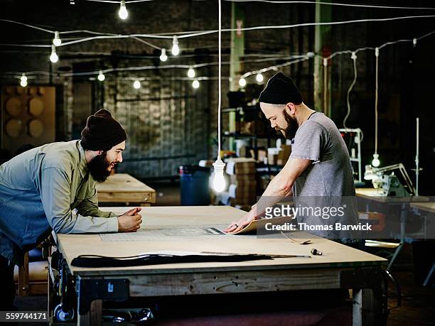 two leatherworkers discussing product design - worktop stock-fotos und bilder