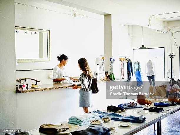 customer completing transaction on digital tablet - clothes shop counter stock pictures, royalty-free photos & images