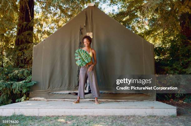 woman holding large leaf outside tent - female bush photos stockfoto's en -beelden