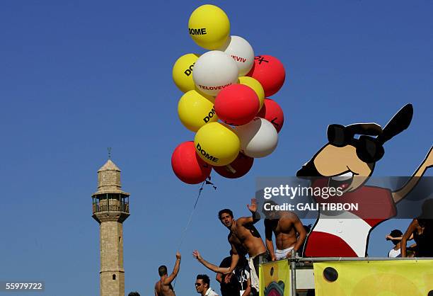 Young Israelis dance at the annual Love Parade at the beach front of Tel Aviv, 21 October 2005, as the minaret of Hassan Beck mosque is seen in the...