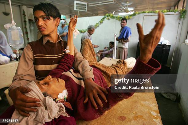 Resham lays in pain after her foot was amputated as Sahir, a family member holds onto her on October 11, 2005 in Muzaffarabad, Pakistan. The doctors...