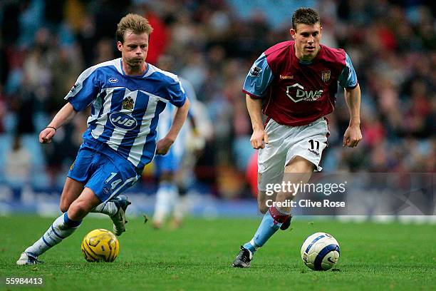 James Milner of Aston Villa is chased by Alan Mahon of Wigan as another ball is thrown onto the pitch from the crowd during the Barclays Premiership...