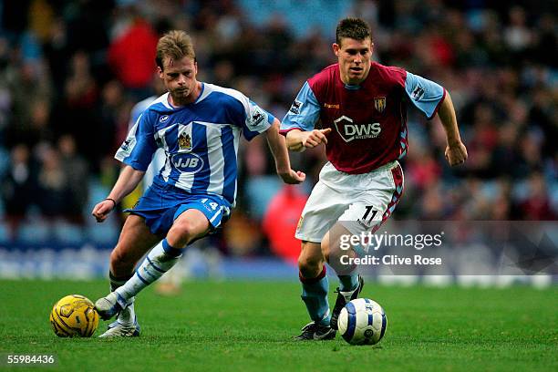 James Milner of Aston Villa is chased by Alan Mahon of Wigan as another ball is thrown onto the pitch from the crowd during the Barclays Premiership...