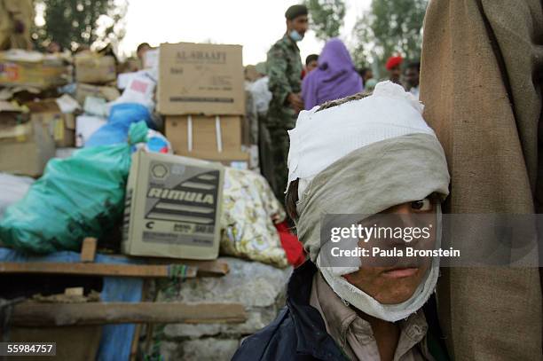 Child injured in the earthquake stands by his father as they wait for blankets being given out by the Pakistani military October 22, 2005 in...