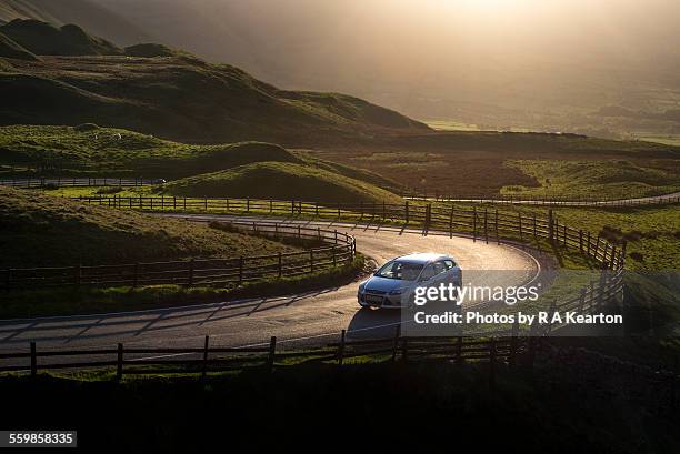 car on a country road at sunset - uk road stock pictures, royalty-free photos & images