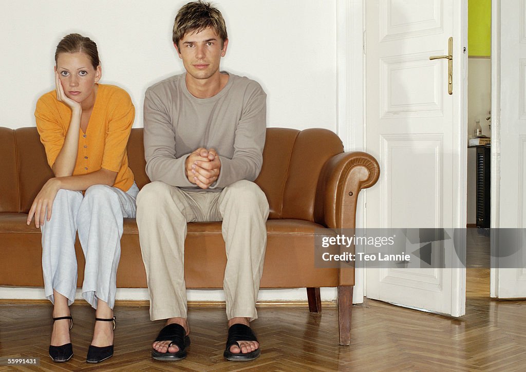 Man and woman sitting side by side on sofa