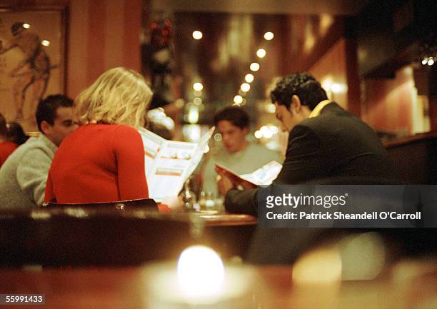 group of young people sitting in restaurant looking at menus - evening meal restaurant stock pictures, royalty-free photos & images