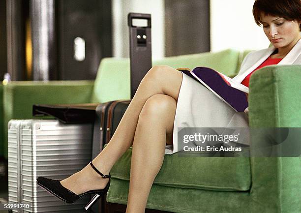 businesswoman sitting in chair reading, legs crossed. - chaise lounge bildbanksfoton och bilder