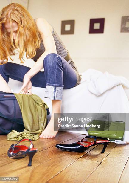 woman sitting on bed looking through bag. - searching mess stock-fotos und bilder