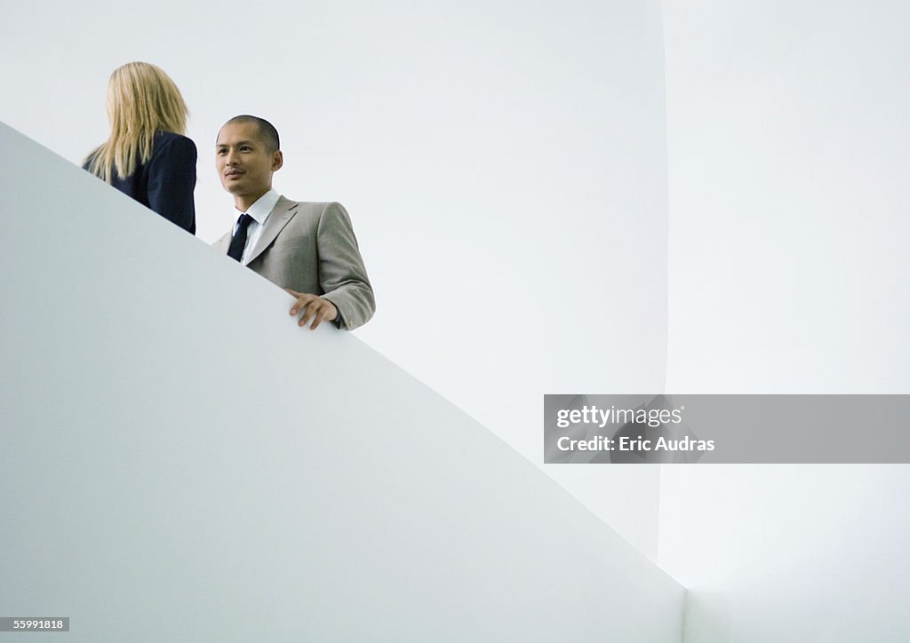 Businessman and businesswoman standing face to face, low angle view