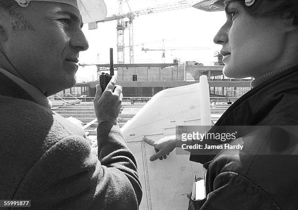 man and woman with hard hats, examining blueprints, close-up, b&w - beton person close stock-fotos und bilder