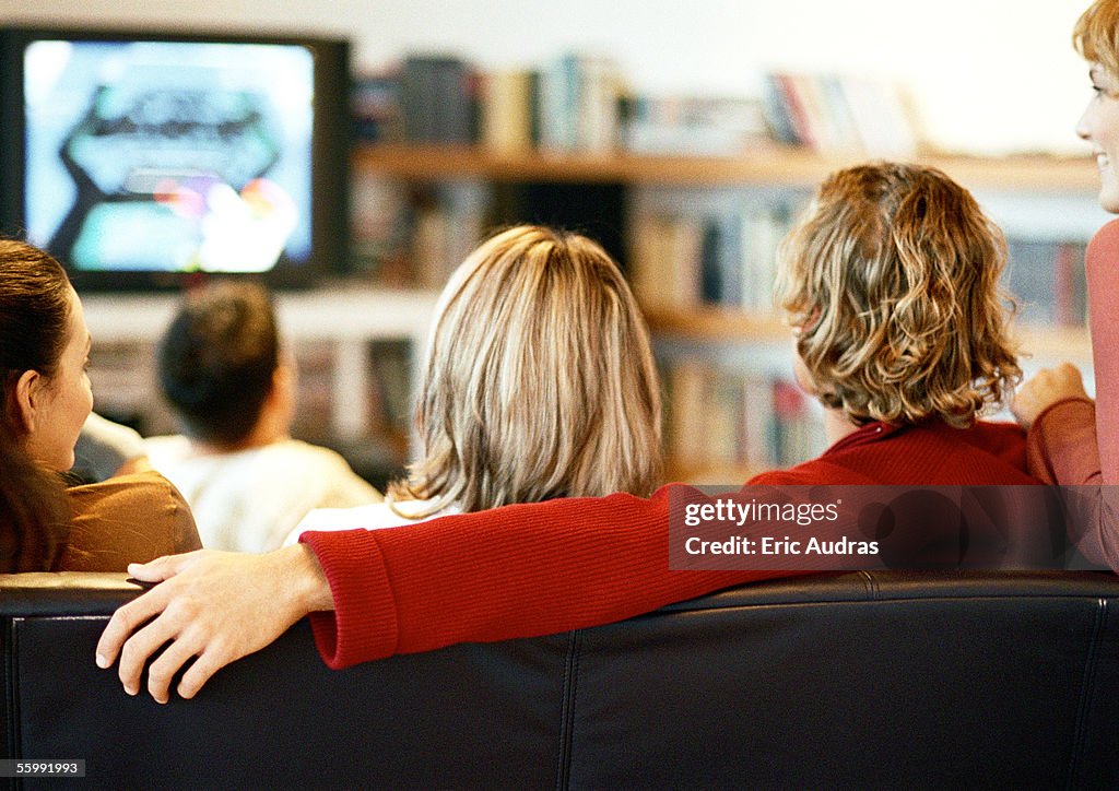 People sitting on couch watching TV, rear view.