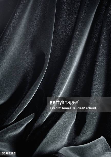 folds in shiny black fabric, close-up, full frame - hochglanz stock-fotos und bilder