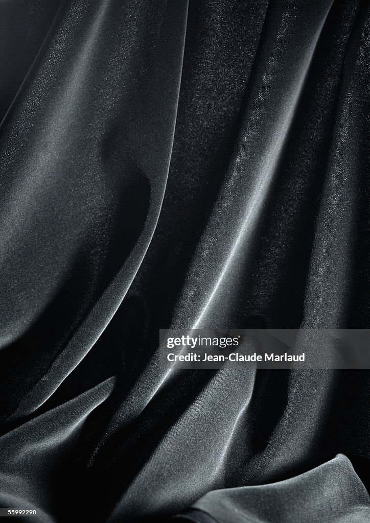 Folds in shiny black fabric, close-up, full frame