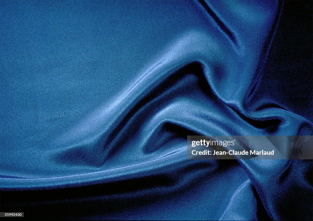 Folds in silky blue fabric, close-up, full frame