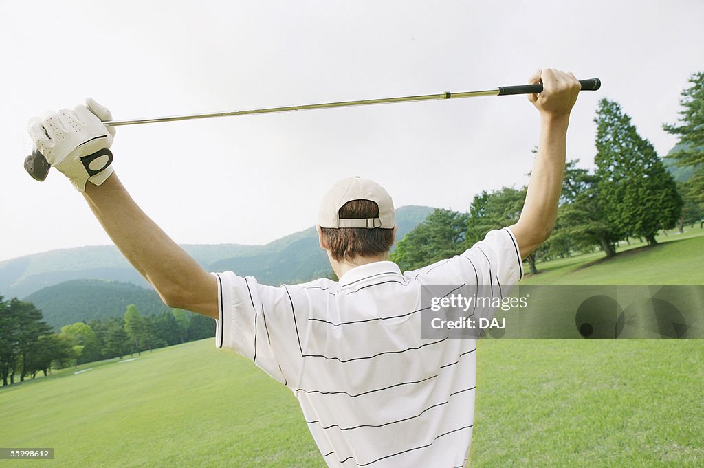 Golfer looking out over green, rear view