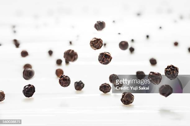 black pepper hit on milk white board - grano di pepe nero foto e immagini stock
