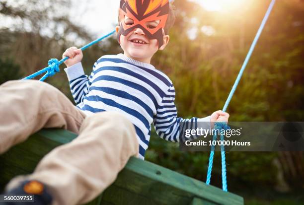 a boy playing on a garden swing wearing a mask - 3 year old stock pictures, royalty-free photos & images