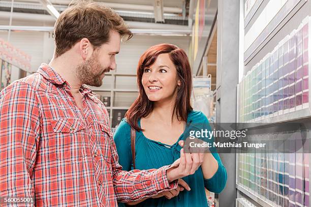 young couple looking for wall paint - baumarkt stock pictures, royalty-free photos & images