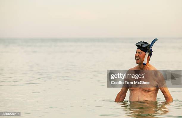 senior male wearing snorkeling gear - waist deep in water stock pictures, royalty-free photos & images