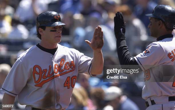 Marty Cordova of the Baltimore Orioles is congratulated by teammate Chris Singeton after Cordova scored against the Kansas City Royals at Kauffman...