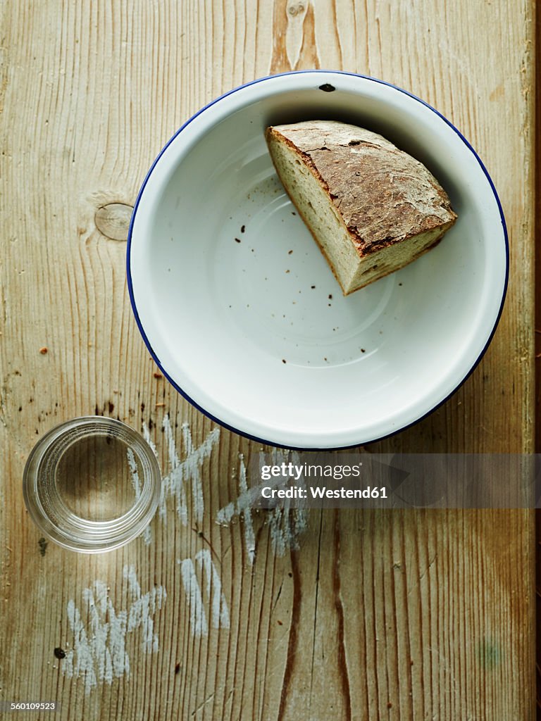 Bowl with crusty end of bread and glass of water