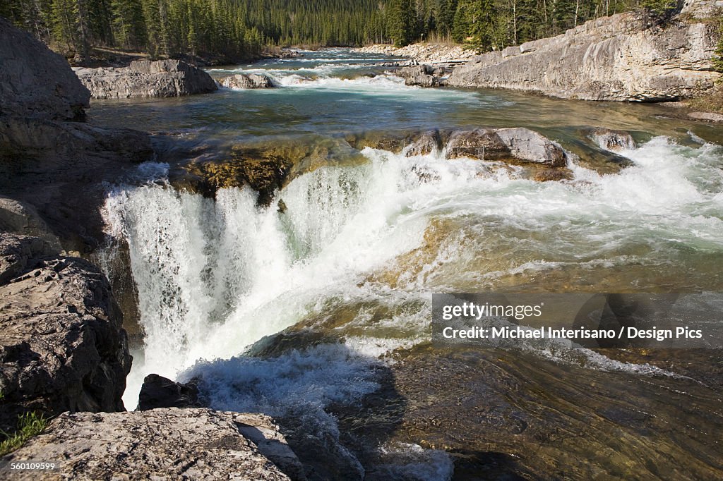 Mountain waterfalls and rushing river with rock cliffs bordering river in kananaskis provincial park