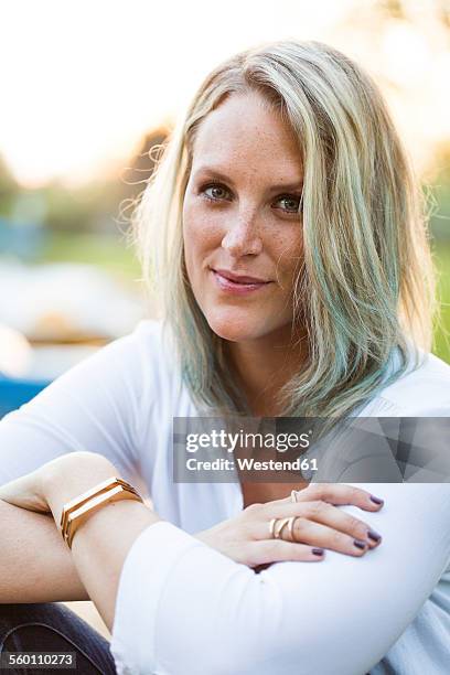 portrait of blond woman with green coloured strand of hair - frau haarsträhne blond beauty stock-fotos und bilder