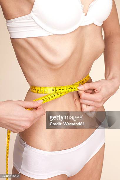 anorexic young woman measuring her waist - anorexie stock pictures, royalty-free photos & images