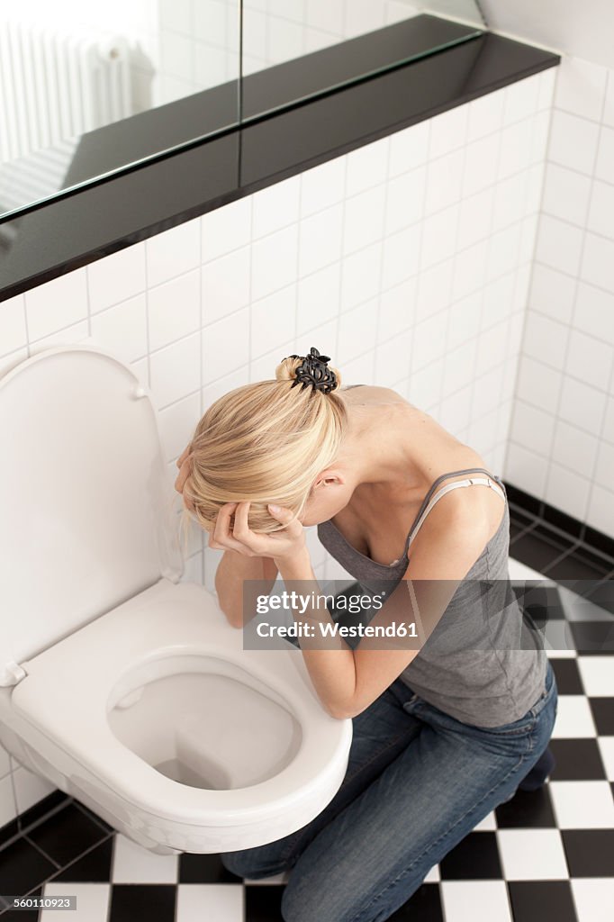 Despaired anorexic young woman at the toilet