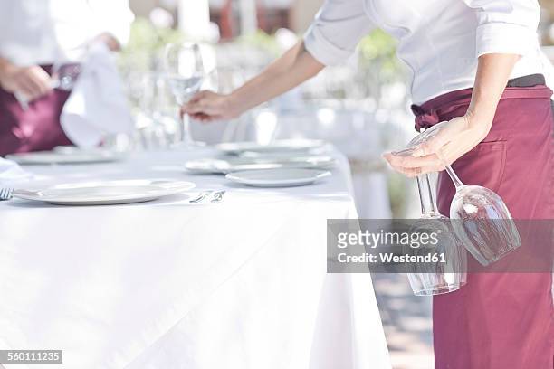waiter placing wine glasses on outdoor restaurant table - positionner photos et images de collection