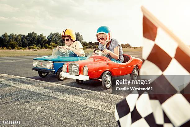 two boys in pedal cars crossing finishing line on race track - macchina a pedali foto e immagini stock