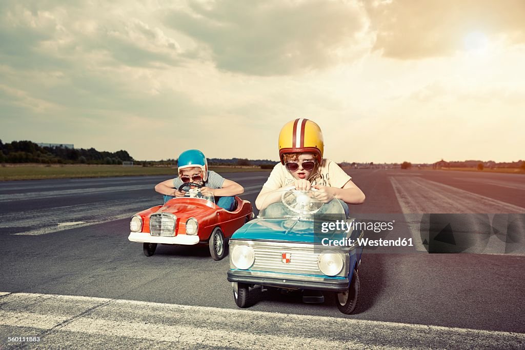 Two boys in pedal cars crossing finishing line on race track