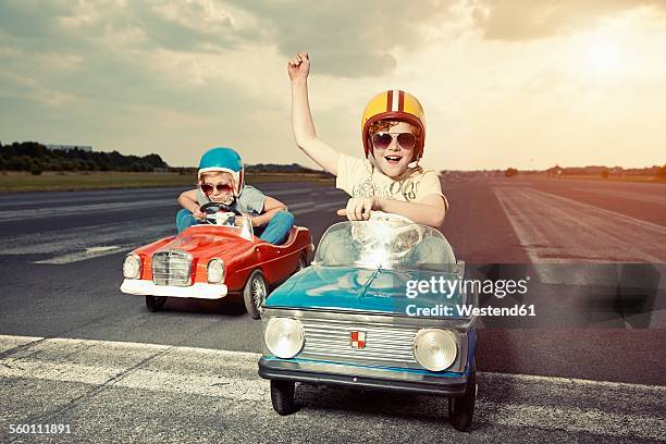 two boys in pedal cars crossing finishing line on race track - soapbox cart foto e immagini stock