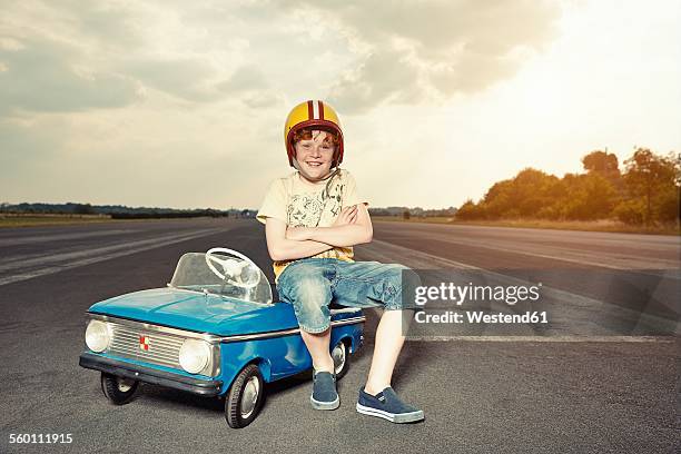 smiling boy with pedal car on race track - go cart stock-fotos und bilder