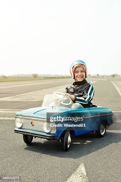 smiling boy in pedal car on race track - macchina a pedali foto e immagini stock