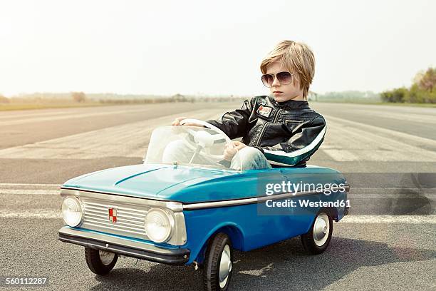 cool boy in pedal car on race track - arrogancia fotografías e imágenes de stock