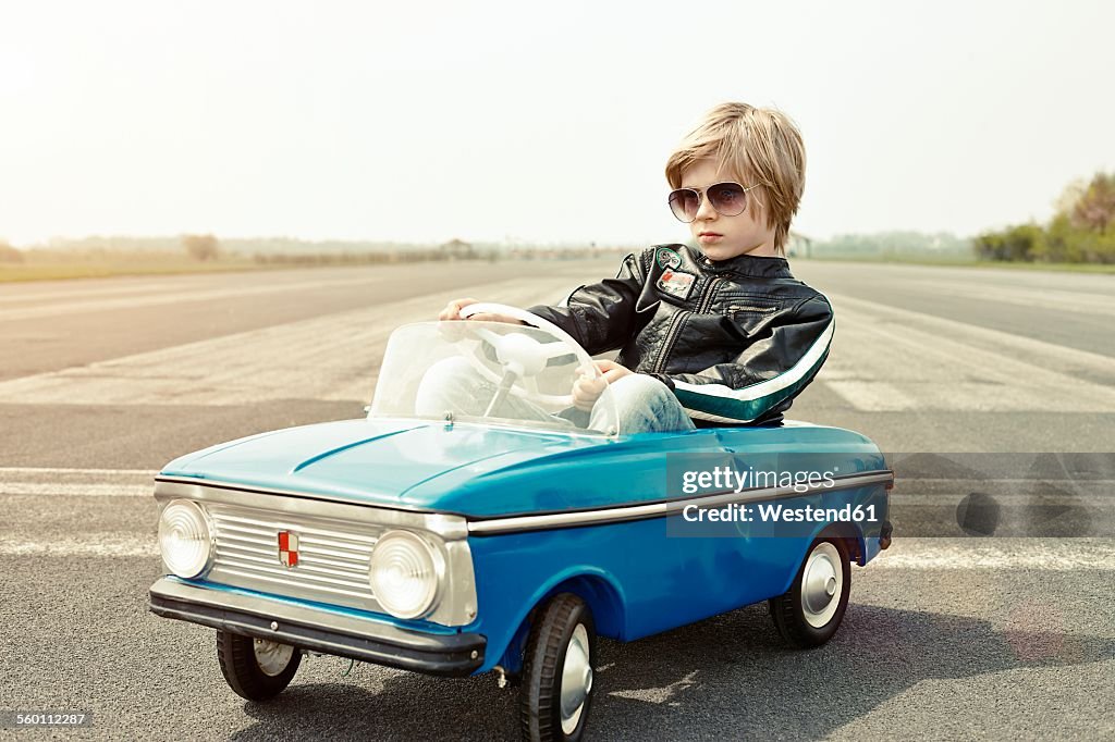Cool boy in pedal car on race track